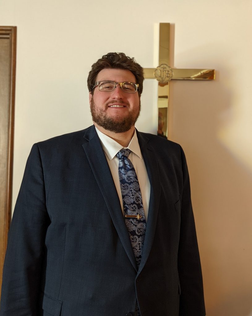 Pastor Aaron Duve standing in front of a cross at Holy Redeemer Lutheran Church