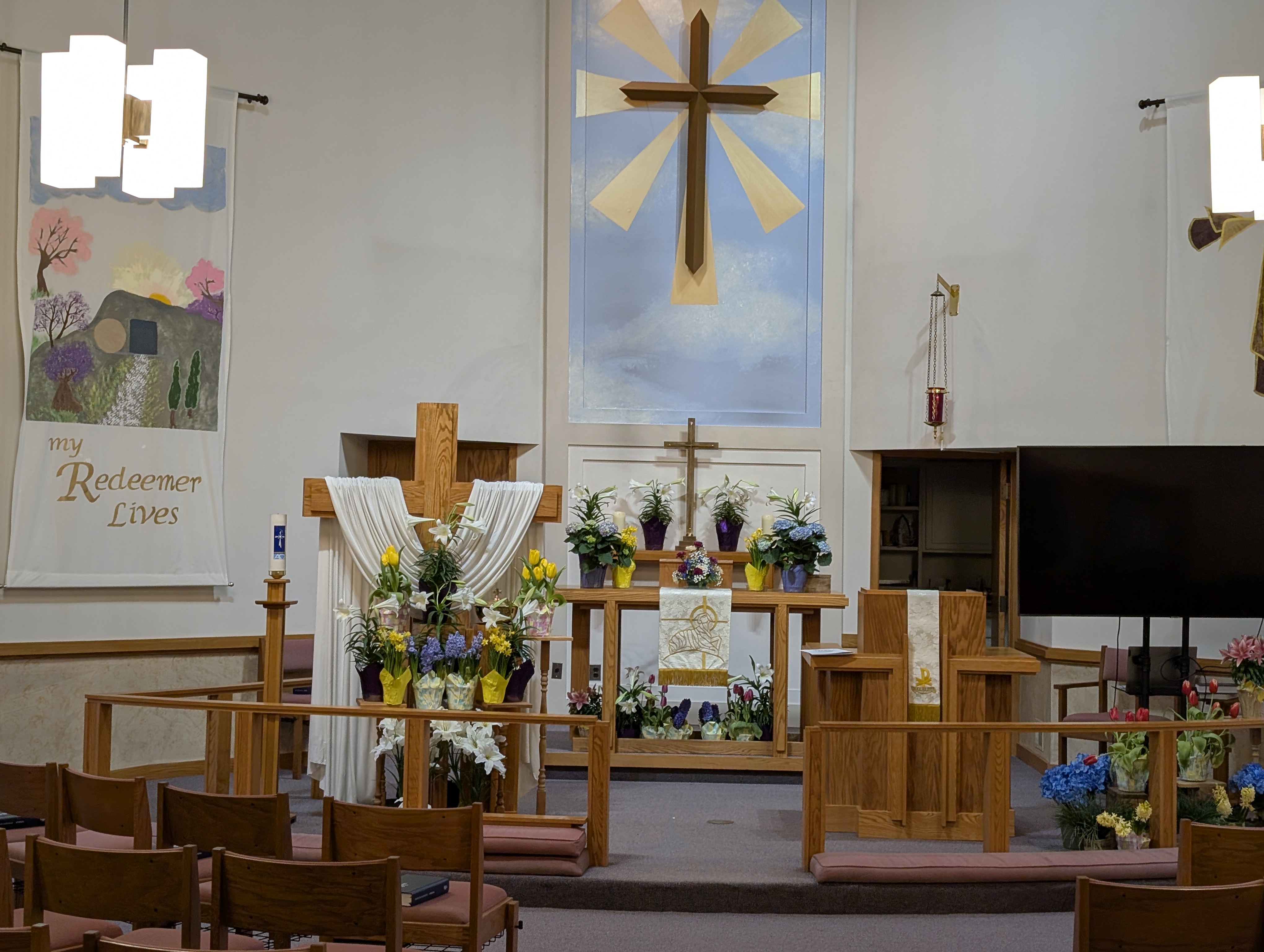 Holy Redeemer sanctuary decorated for Easter, with the cross and 'My Redeemer Lives' banner