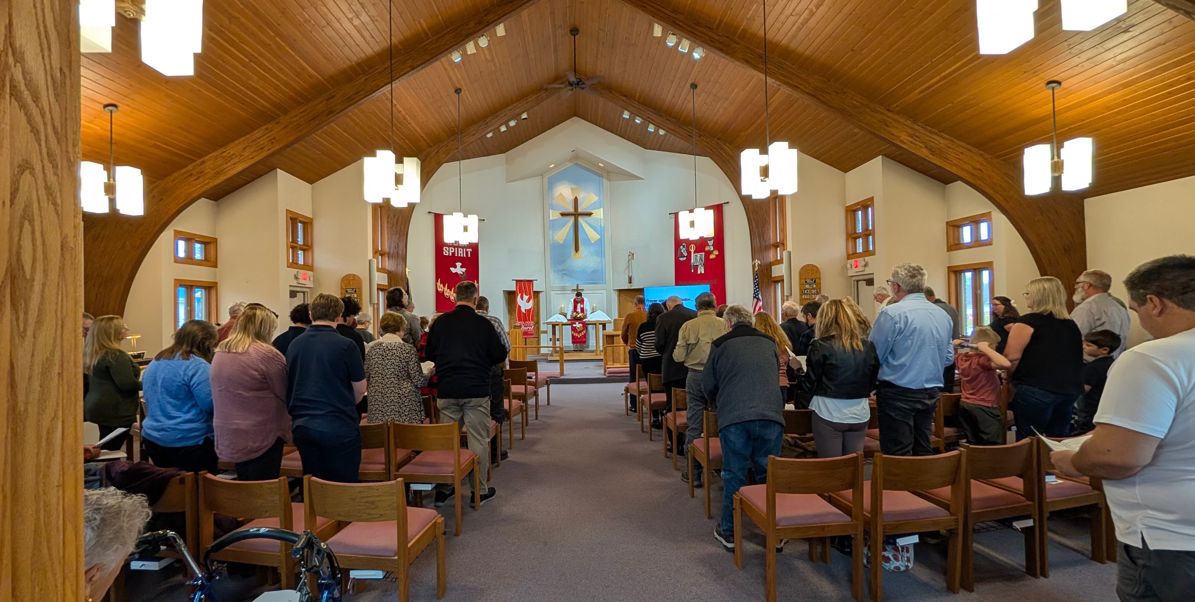 Pastor Duve leading worship as the congregation stands in prayer